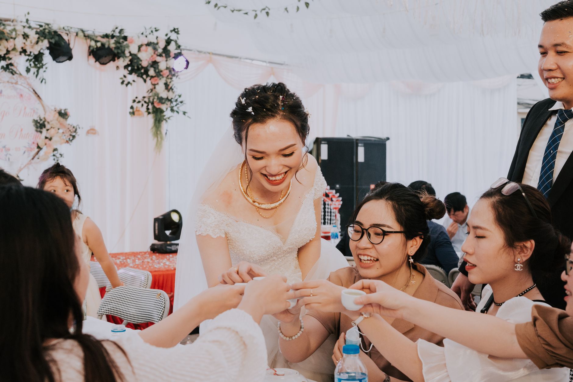 Laughing young Asian bride and groom clinking with sake cups while toasting for happiness of newlyweds